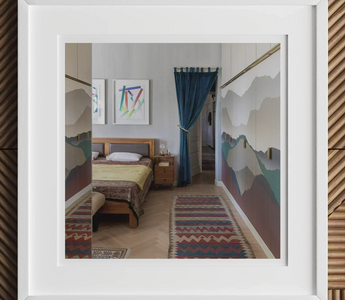 Wooden bed with colorful bedding and mountain-themed wall art showcasing bold patterns in maximalist aesthetics