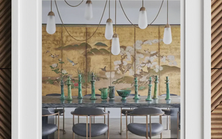 Dining table set with green glass vases and hanging pendant lights featuring statement pieces in minimalist maximalist design