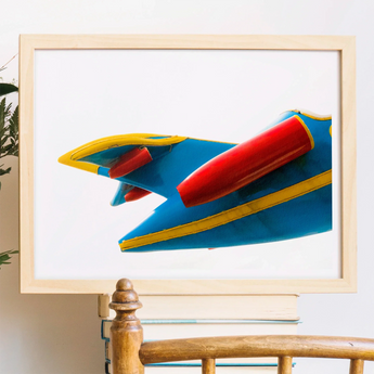 Colorful retro-style rocket or spaceship artwork in a wooden frame.