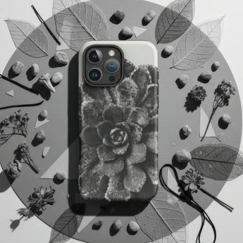 IPhone case with a black and white nature-inspired design featuring spiral shells and pine trees.