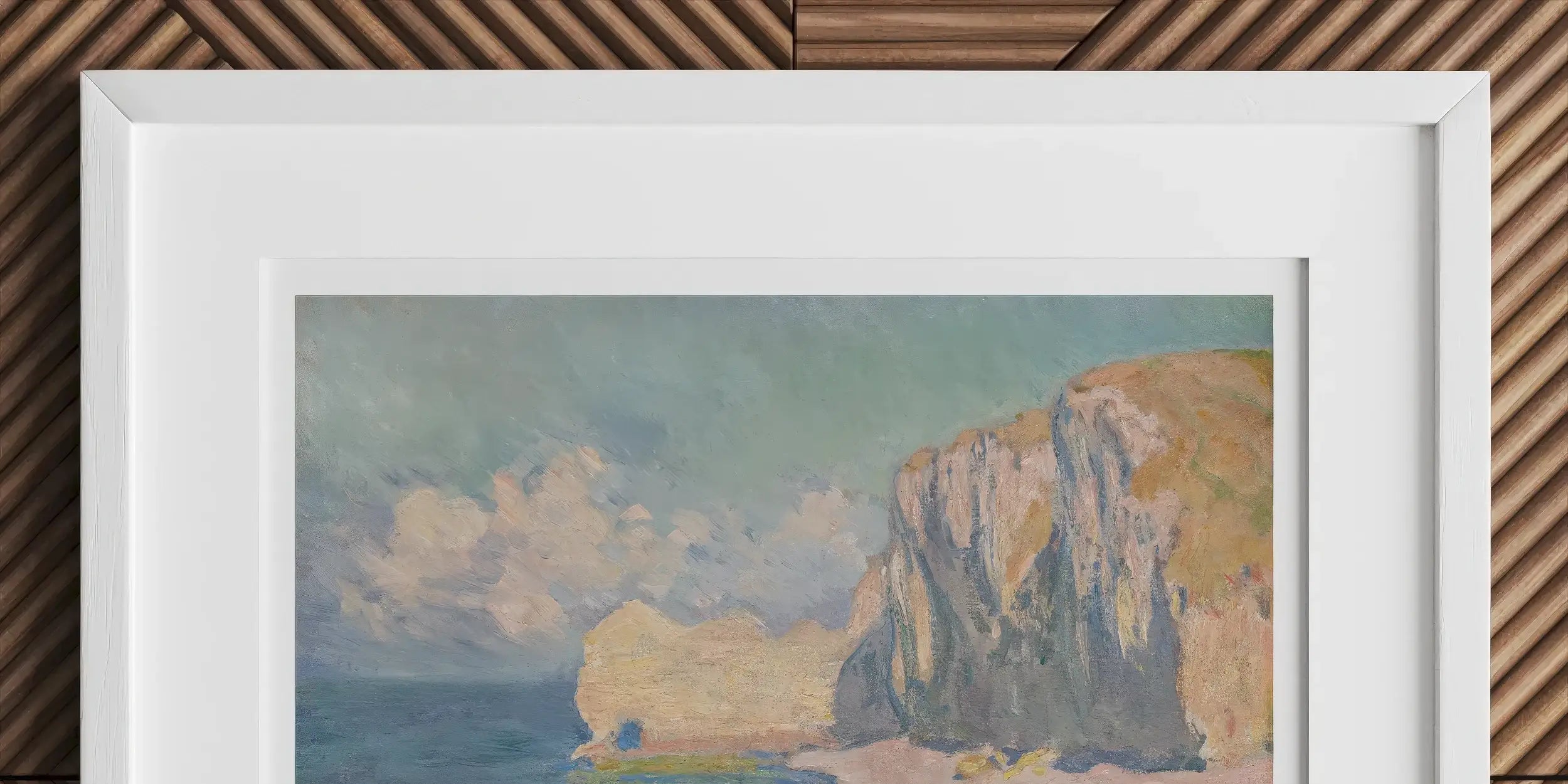 Framed painting of a coastal scene with cliffs, beach, and boats on the water.