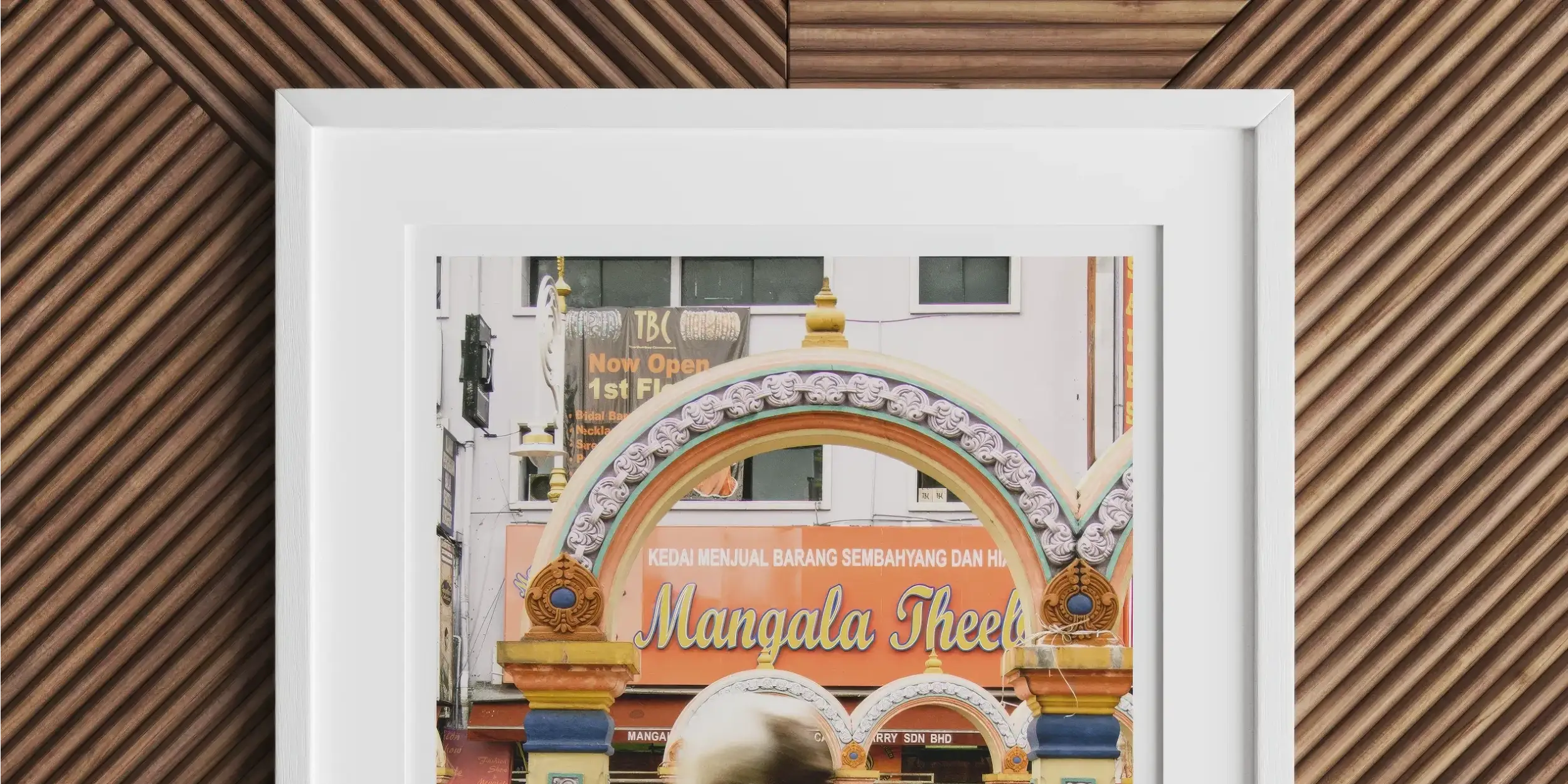 Framed photograph of a colorful archway labeled ’Mangala Street’ with a blurred figure in yellow passing by.