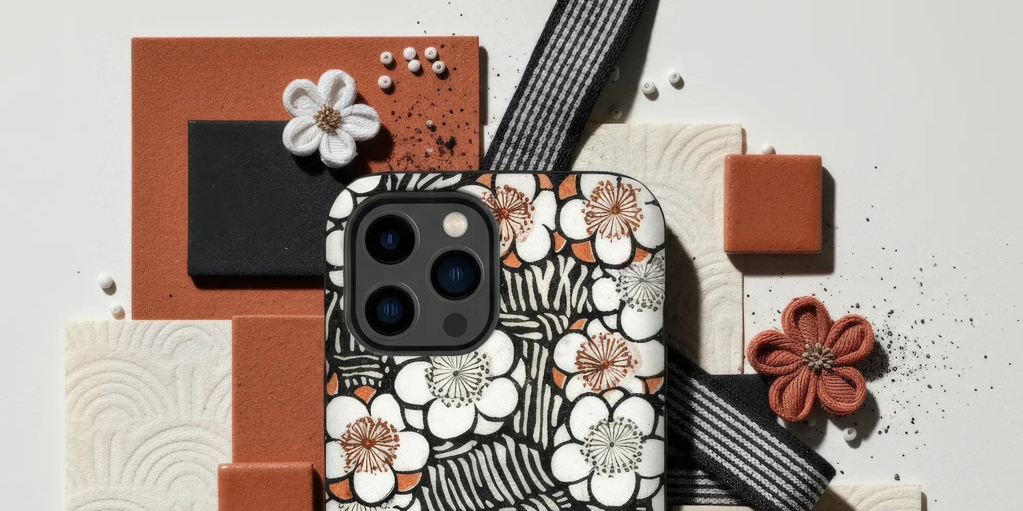 Floral patterned laptop sleeve or case with white and orange blossoms on a black and white striped background.
