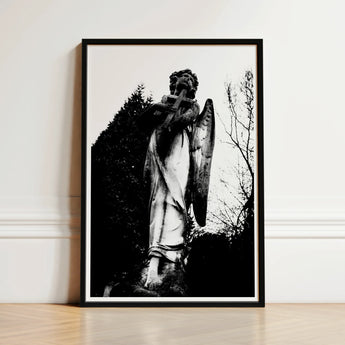 Black-framed Black-and-white Photograph Weathered Stone Angel Statue Cross Figure Carved