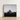 Minimalist Black-and-white Framed Photograph Solitary Stone Open Field Brick House with Muted Silver, Blank Sky Cloud Cover, Light Seeps