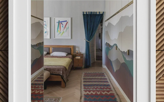 Wooden bed with colorful bedding and mountain-themed wall art showcasing bold patterns in maximalist aesthetics
