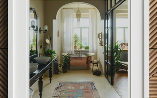 Elegant white clawfoot bathtub beneath arched window with sheer curtains highlighting sustainable interior design and air quality