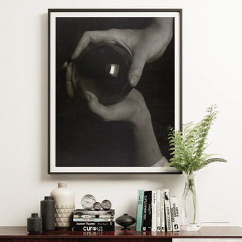Framed black and white hands holding a crystal ball.