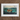 Framed painting of a person in a small boat on stormy seas with sharks nearby.