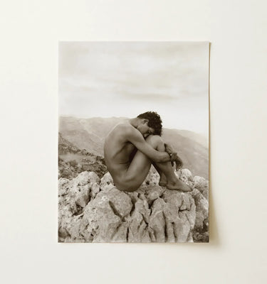 Image of a nude young man perched on rocks, embodying themes from the art of Baron Wilhelm von Gloeden.