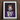 Framed portrait of a person wearing a crown, vampire fangs, and elaborate jewelry against a dark background.
