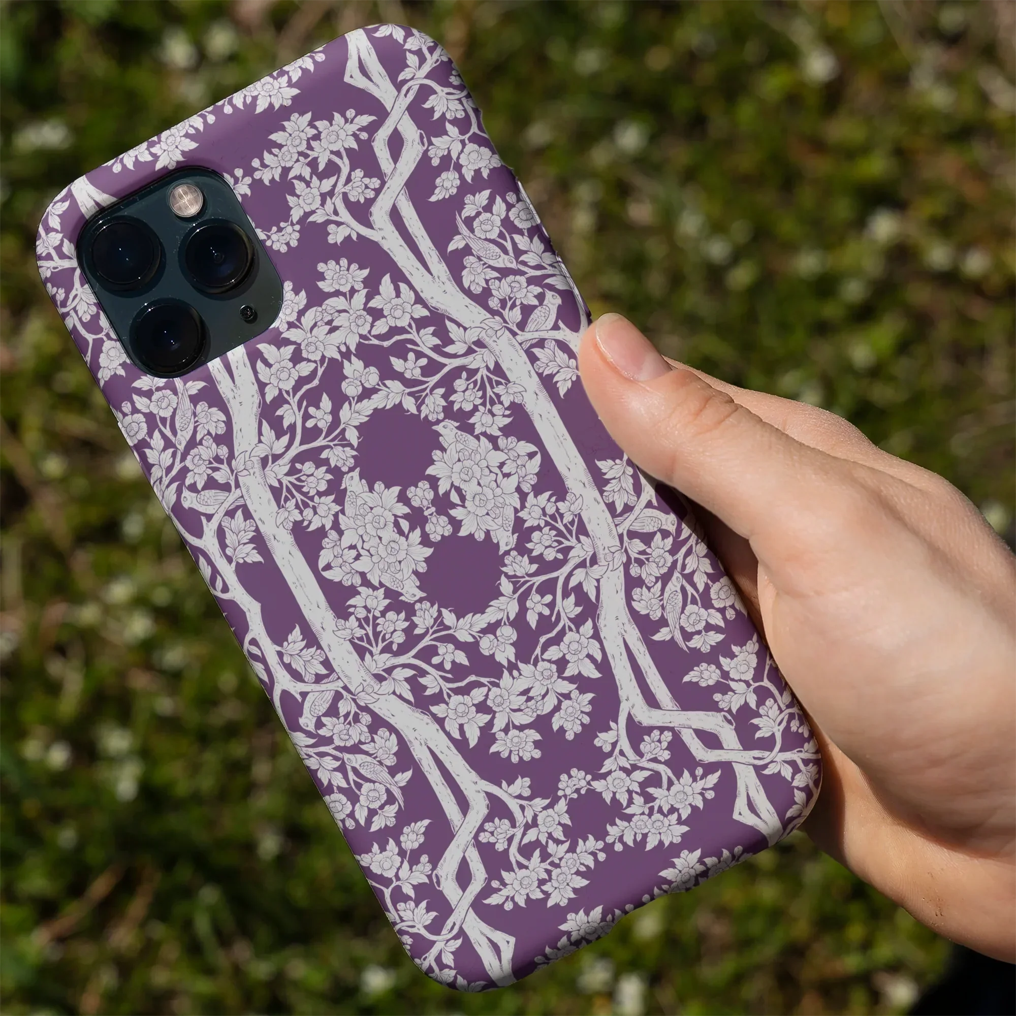 Purple iPhone case with an intricate white floral and vine pattern.