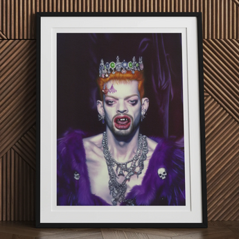 Framed portrait of a person wearing a crown, vampire fangs, and elaborate jewelry against a dark background.
