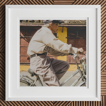 Framed photograph of an elderly person riding a bicycle.