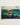 White-framed artwork of a wooden boat with two figures battling teal ocean waves and sharks from winslow homers collection