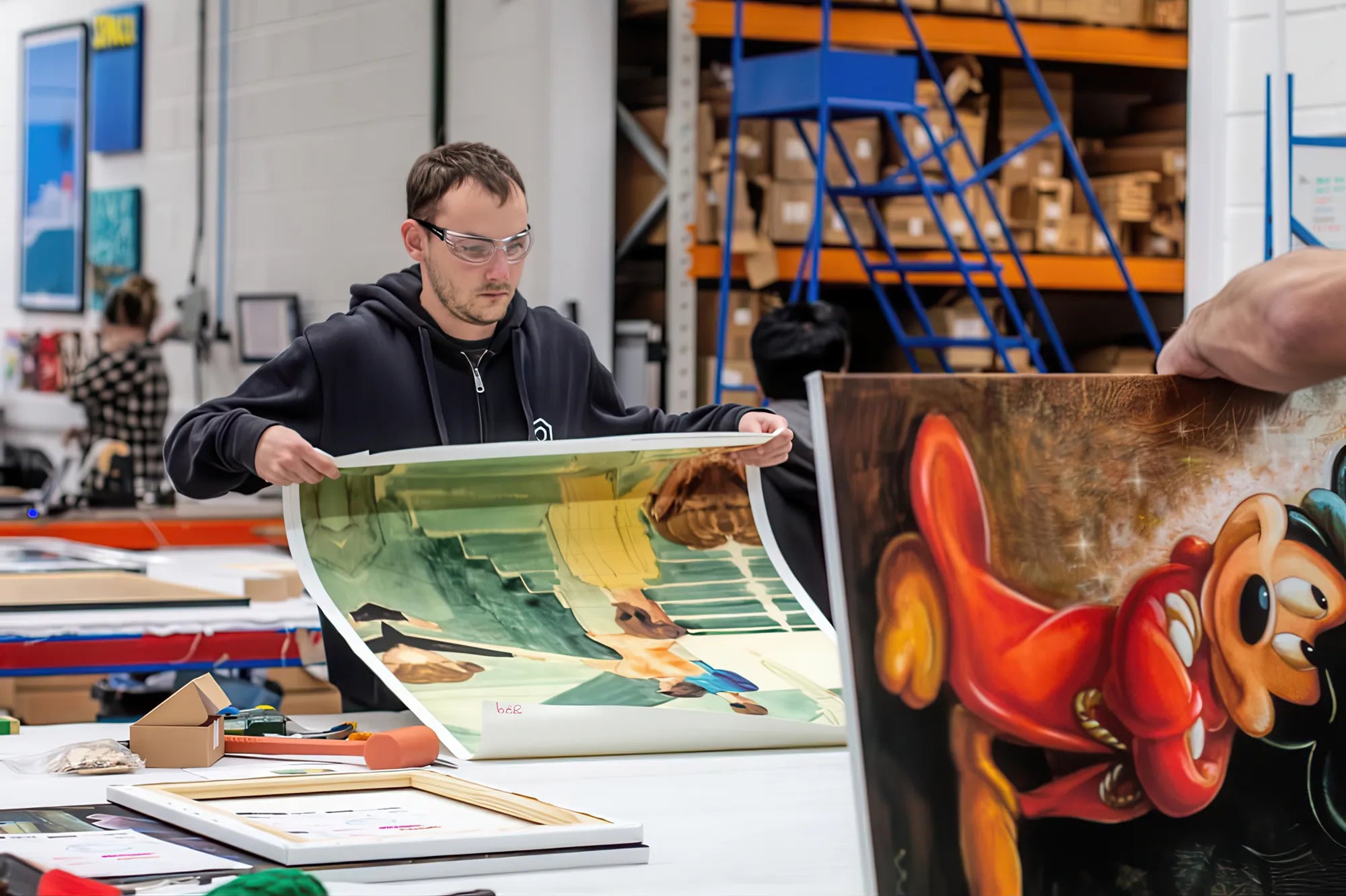 Someone examining what appears to be an animation cel or artwork print in a workshop setting