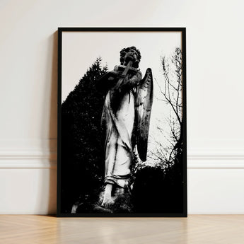 Black-framed Black-and-white Photograph Weathered Stone Angel Statue Cross Figure Carved