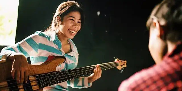 Bass guitar being played with a joyful expression.