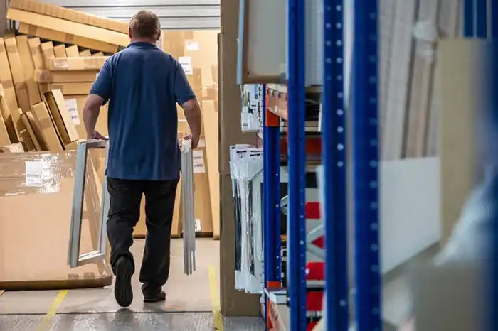 Someone walking through a doorway while carrying what appears to be furniture or building materials.