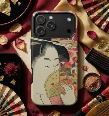 A smartphone case featuring a vintage Japanese ukiyo-e style illustration of a woman holding a fan, styled in a flat-lay with traditional props including a comb, powder bowls, dried petals, and folding fans on a dark red fabric background.