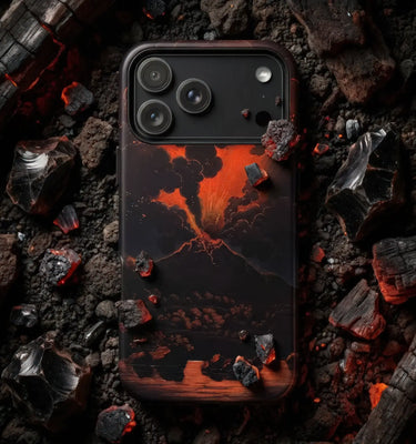 A smartphone case featuring a dramatic volcanic eruption design in glowing orange and red lava tones against a dark background, shown resting on scattered charcoal and embers.
