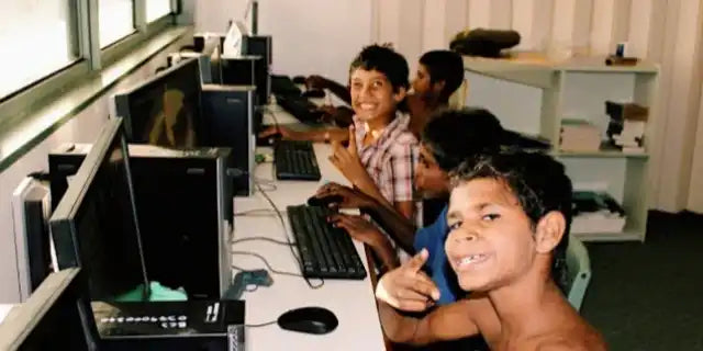 Students working at computer workstations in what appears to be a classroom or lab setting.