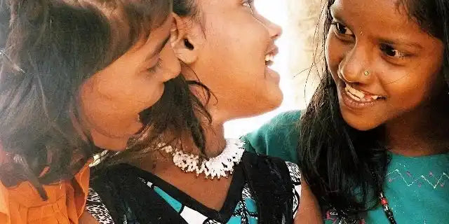 Three children sharing a joyful moment together, with bright smiles and laughter.