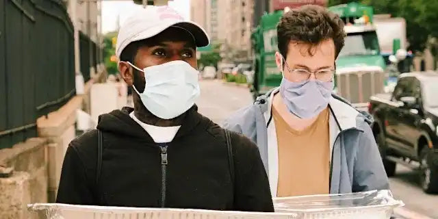 Two people wearing protective face masks while carrying delivery trays.