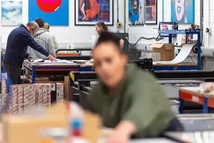 Workshop or studio space with printing equipment and artwork displayed on the walls.